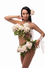 Sensual young woman with flowers on naked body touching face in studio