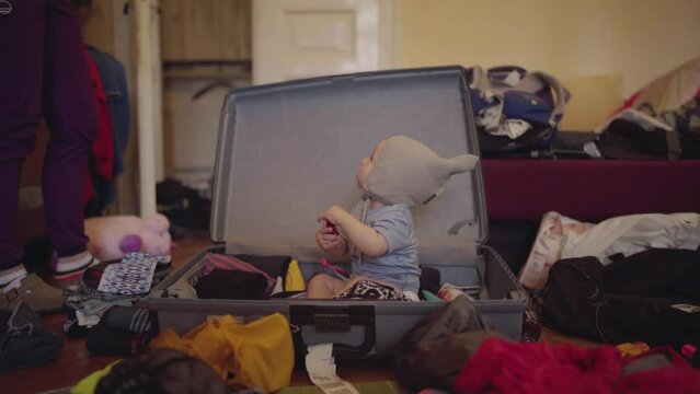 Cute Baby Boy With Knit Hat Sitting In Suitcase At Home - Jablonec nad Nisou, Czechia