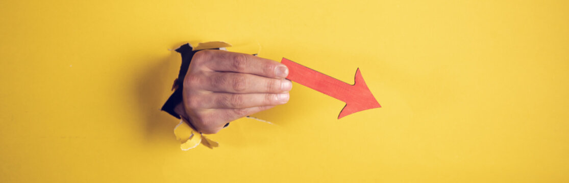 man holding wooden down arrow in hand
