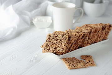 Crackers with sunflower seeds and flax seeds on a white table.