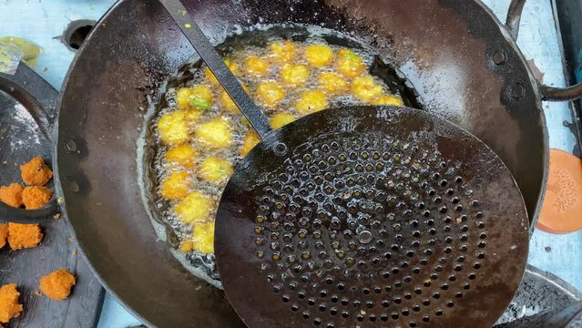 Close up shot of moong dal pakora being fried in hot oil in big Kadhai in the street of Kolkata for sale. India