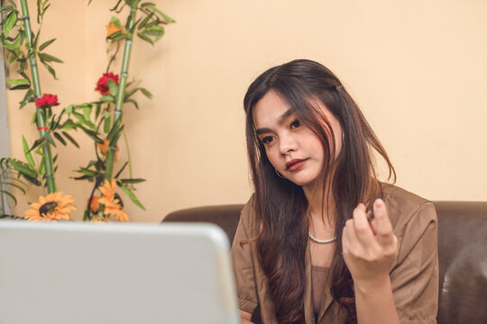 Young Adult Woman Wearing Brown And With Beautiful Make Up Seriously Thinking Showing Mannerism With Her Fingers