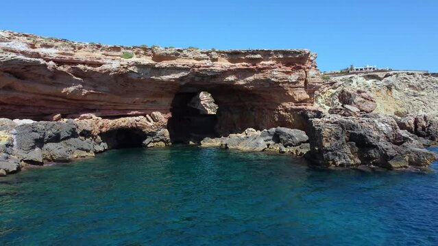 cliff edge secret pirate smuggler cave natural bridgeMarvelous aerial view flight fly forward drone footage to cave beach Sa Figuera borda Ibiza summer 2022 
