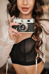 beautiful sexy brunette with a beautiful figure in sexy lingerie with a vintage camera