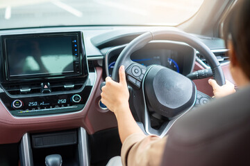Obraz premium woman driver driving a car on the road, hand controlling steering wheel in electric modern automobile. Journey, trip and safety Transportation concepts