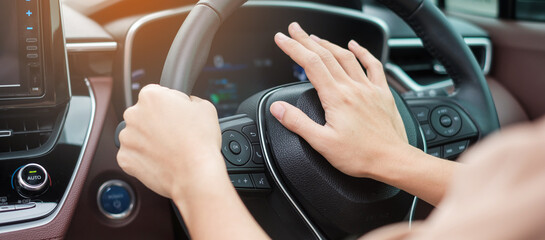 woman driver honking a car during driving on traffic road, hand controlling steering wheel in...