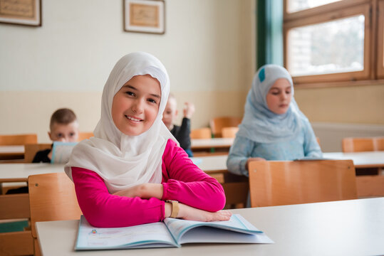 Group of happy Muslim school children sitting at the desk in the classroom.