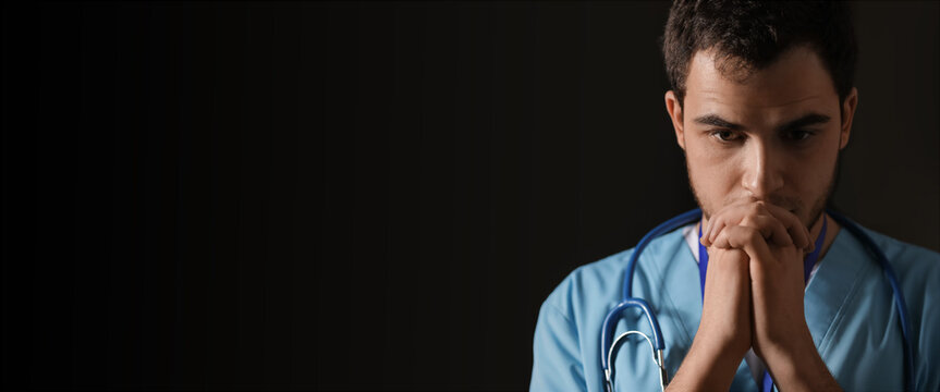 Praying Male Doctor On Dark Background With Space For Text