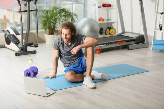 Sporty young man video chatting with coach in gym