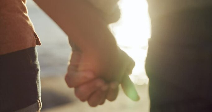 Romantic, in love couple holding hands on the beach showing love, affection and care enjoying a beautiful sunset sea view. Romance closeup of a boyfriend and girlfriend bonding together by the ocean