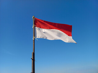 A waving Indonesia national flag with a blue sky as the background to commemorate the Indonesia independence day. 