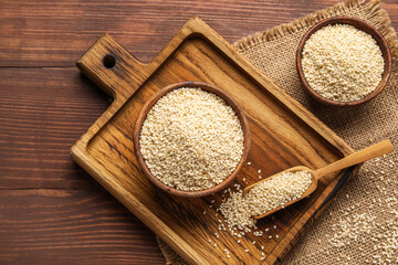 Composition with bowls and scoop of sesame seeds on wooden background