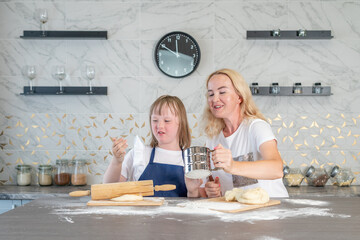 girl with down syndrome and her charming mother, bake dough pies in the kitchen of their house and...
