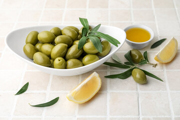 Bowls of green olives, oil and lemon slices on color tile