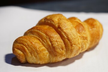 Golden yellow croissant, often paired with coffee. placed on white paper