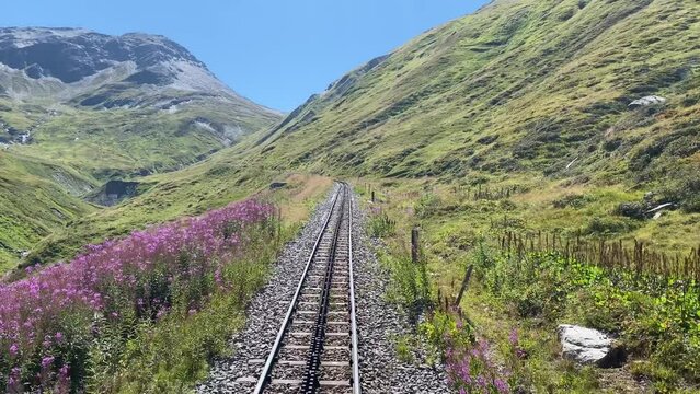 Steam railroad in the Swiss Alps goes over the Furka Pass with a toothed rack railroad. The old railroad line runs high above the mountains