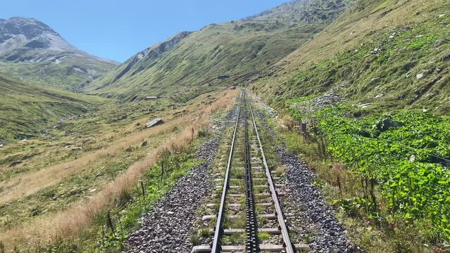 Steam locomotive in the Swiss Alps travels over the Furka Pass with a cogwheel railroad. The old railroad line runs high above the mountains