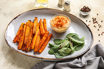 Plate of tasty baked carrots, greens and sauce on table, closeup