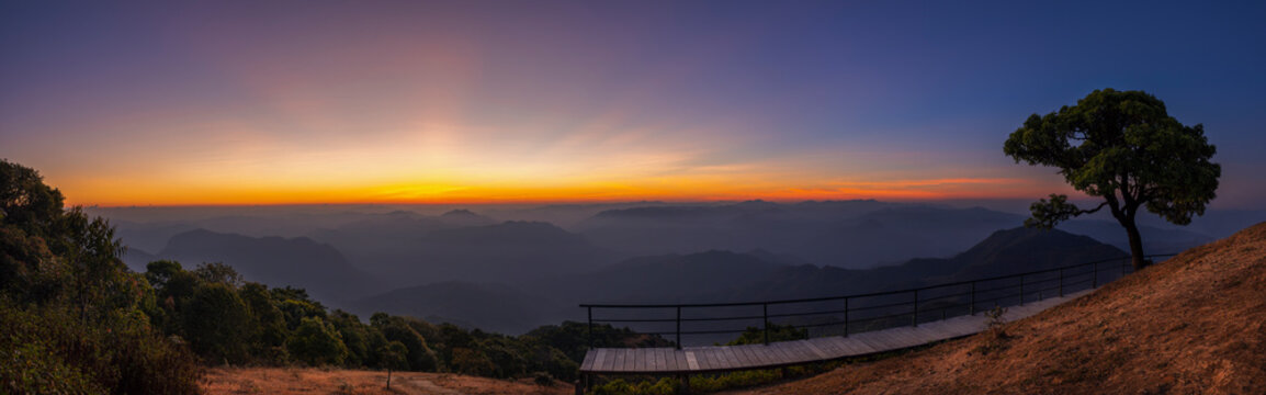 A panoramic view of the morning with the sun rising on the horizon for a beautiful time with Lonely tree and pathway beside the hill at Doi Pui Co view point in Sop Moei, Mae Hong Son Thailand.