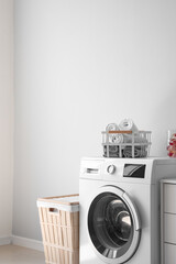 Washing machine with basket, towels and capsules near light wall in laundry room