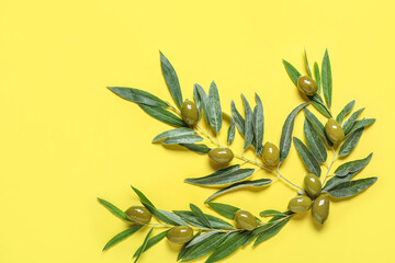 Fototapeta na wymiar Green olives and leaves on yellow background