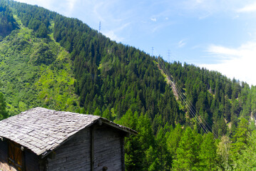 Fototapeta na wymiar Scenic alpine landscape with wooden hut at mountain village Oberwald, Canton Valais, on a sunny summer day. Photo taken July 3rd, 2022, Oberwald, Switzerland.