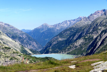 Fototapeta na wymiar Scenic view of dam lake with mountain panorama in the background at Swiss mountain pass Grimsel on a sunny summer day. Photo taken July 3rd, 2022, Grimsel Pass, Switzerland.