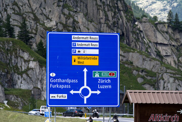 Blue direction sign at roundabout at mountain village Andermatt, Canton Uri, on a sunny summer day. Photo taken July 3rd, 2022, Andermatt, Switzerland.
