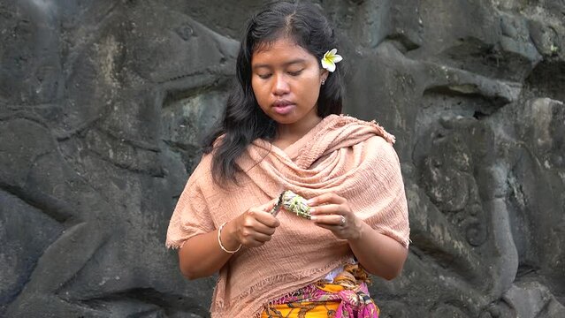 Young Beautiful Balinese Indonesian Woman light White Sage for Blessing Hindu Ceremony wearing Traditional clothing in Scenic Temple