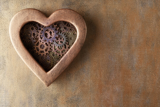Gears on heart shaped box on metal background with copy space