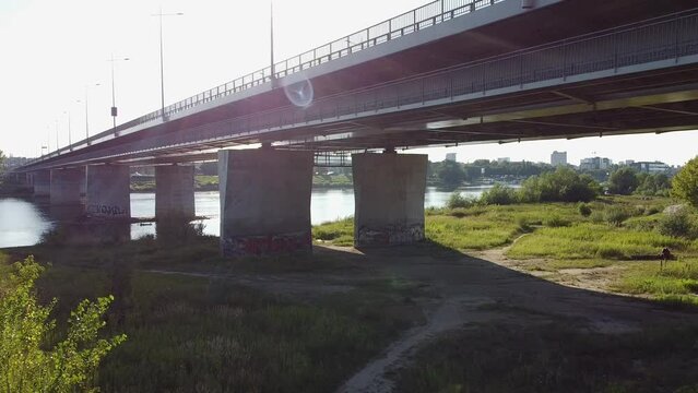 Aerial drone shot of under the bridge while a person carries and walks looking to vista river Warsaw Poland