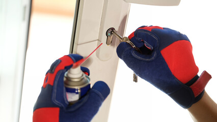 Repairman using lubricate in spray can for lock of plastic window