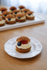 Homemade choux cream or cream puffs with custard cream and strawberry. Homemade bakery concept.