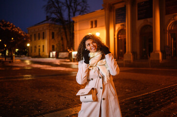 Smiling black woman in front of a old theater with cobblestones in the night