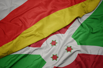 waving colorful flag of burundi and national flag of south ossetia.