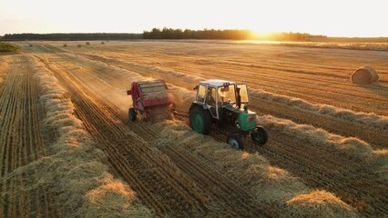 Agricultural machine making hay bale make round large bales. Haymaking. Hay making machine at sunset. Tractor collecting hay and making haystacks.