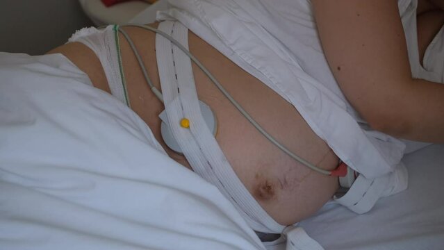 Pregnant woman with cardiotocography belt having contractions in delivery room of hospital. Preparing for bring forth