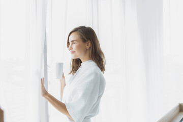 beautiful woman drinking coffee or milk in the morning by the window. view from outside. She drinking milk after wake up in the morning