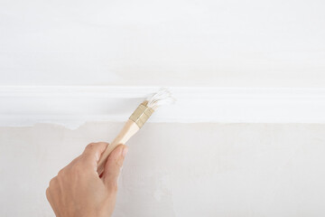 hand painting skirting boards white with a brush.