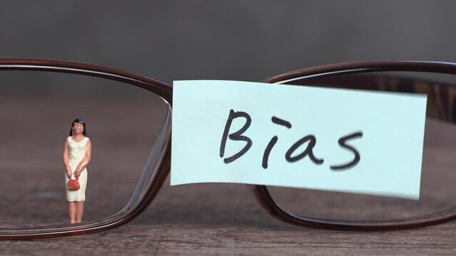 Pieces of paper and eyeglasses with a 'Bias' swaying in the wind. Business concept with glasses and miniature woman.
