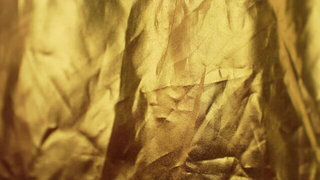 Wrinkled golden color cloth background with changing light