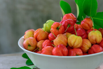 Fresh Acerola cherry, Barbados cherry, and green blur background, High vitamin C and antioxidant fruits.