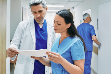Experienced cardiologist with female nurse analyzing patient cardiogram. Department of cardiology...