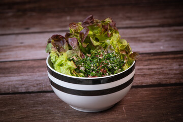 Parsley salad or Tabbouleh, easy and healthy classic vegetarian dish with bulgur, tomatoes, parsley, spring onion and mint, olive oil on dark wooden background, High quality photo