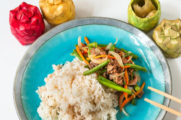 Rice and fried beef, onion,green bean and carrot on blue plate, chopstick and 4 bamboo box with condiment.