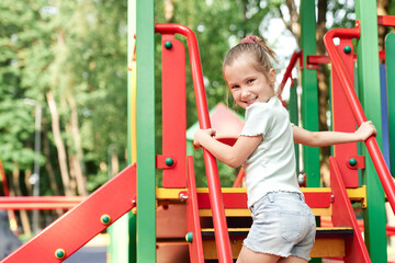 Caucasian little girl playing at playground in summer day