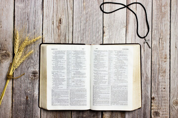 An open Bible with cross over the wooden table. 