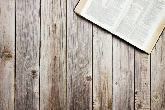 An open Holy Bible over the wooden background with copy  space.