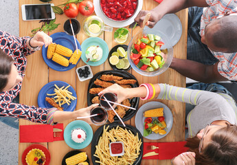 Top view of group of people having dinner together while sitting at wooden table. Food on the table. People eat fast food.