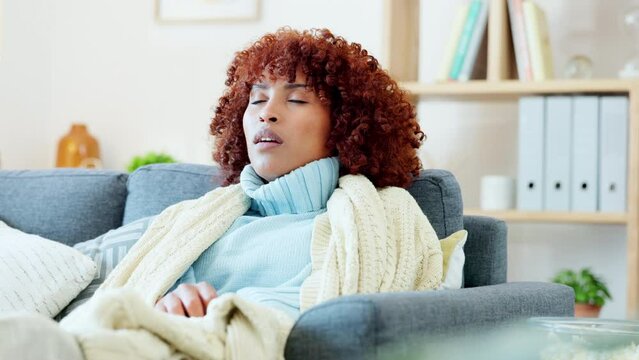 Sick, coughing and sneezing woman feeling ill and tired from flu, cold or covid at home inside. Young female indoors holding a tissue with corona virus sitting on a living room lounge couch